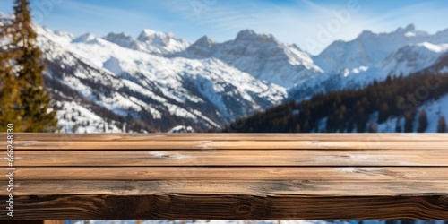 A dark wood table on the cabin deck offers perfect views of a snow-covered forest, icy lake, and snow-capped peaks.