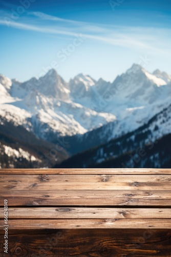 A dark wood table on the cabin deck offers perfect views of a snow-covered forest, icy lake, and snow-capped peaks. © TETIANA