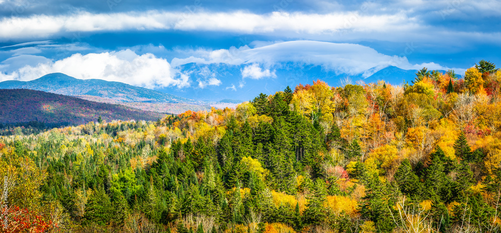 Panoramic view of New Hampshire fall foliage colors with clouds covered Mount Washington, in the background, as viewed from Bethlehem's NH Main street, on a sunny afternoon