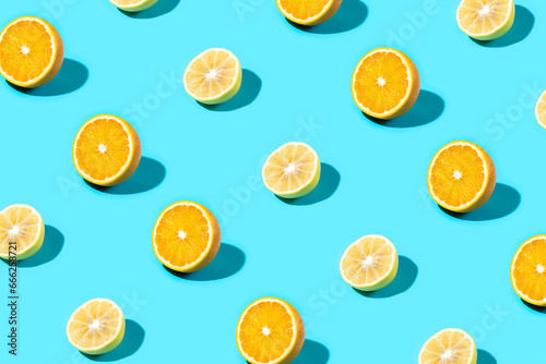 Trendy Summer food pattern made with yellow lemon and orange slice on bright light blue background. Minimal summer concept.