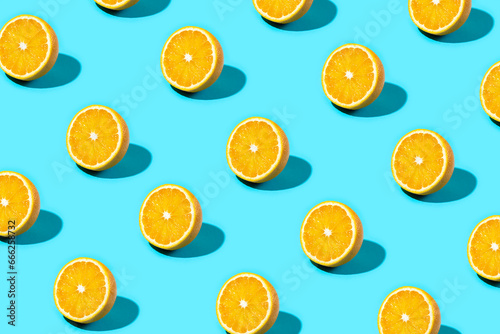 Trendy Summer food pattern made with orange slice on bright light blue background. Minimal summer concept.