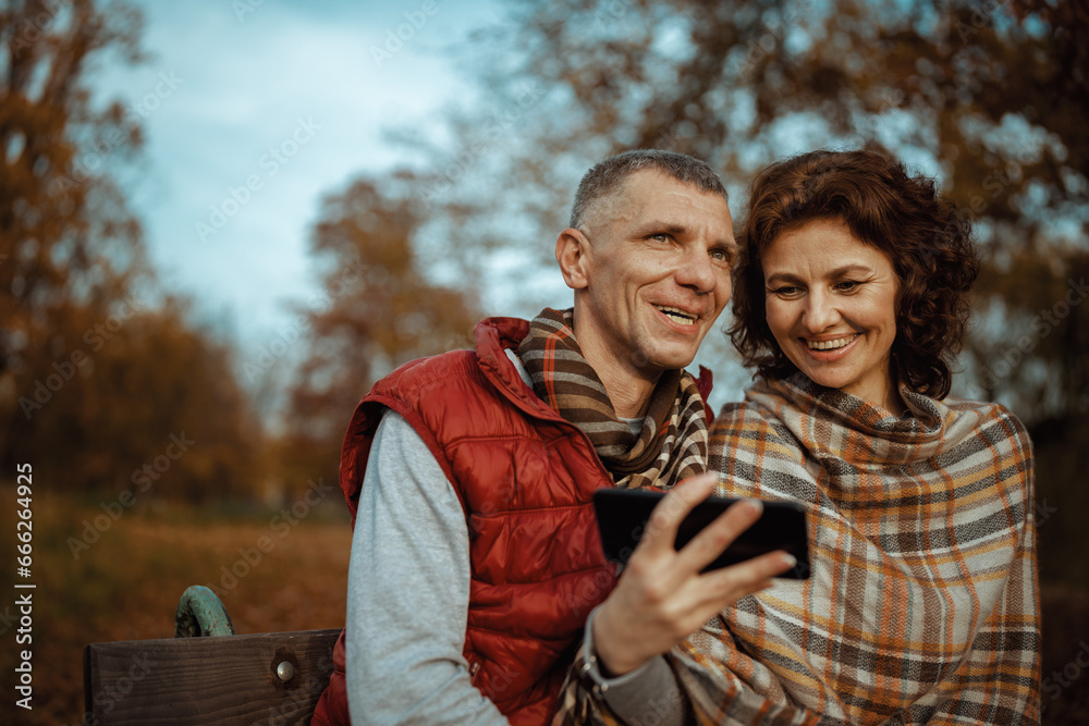 smiling modern couple in park with smartphone