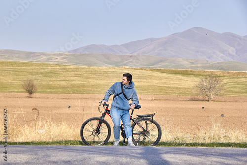 A teenage tourist with a bicycle on the background of the highlands in the fresh air