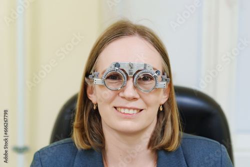 Middle-aged woman wearing glasses for eye exam in ophthalmologist's office.