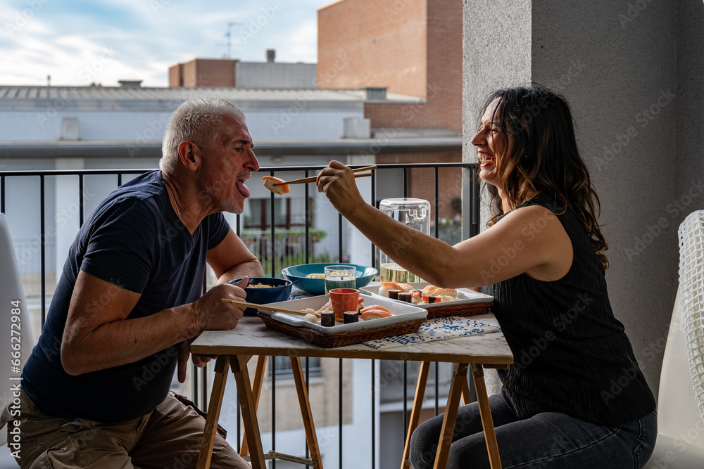 beautiful middle aged couple eating Chinese take away food sitting at a laid table - obrazy, fototapety, plakaty 