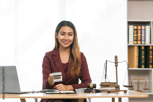 Young Asian female lawyer people reviewing legal documents at desk, embodying reliability, dedication in legal profession, reading announcement. Court convicting defendant according to criminal law