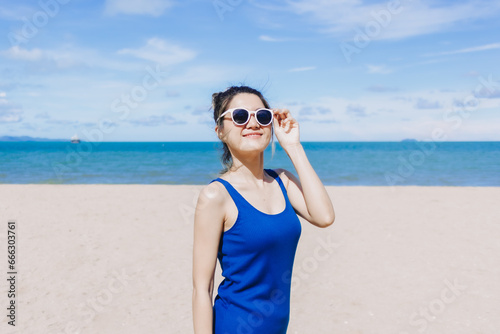 Happy and cheerful asian woman in blue dress on the sunny beach of Thailand. © Sevendeman