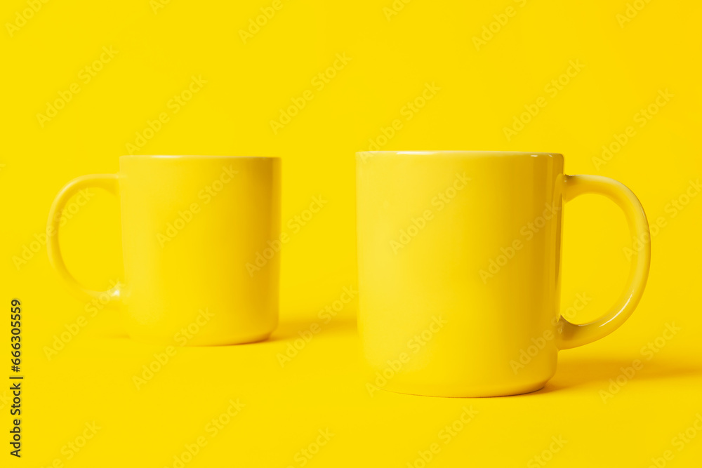 Two bright ceramic mugs on yellow background Two bright ceramic mugs on yellow background