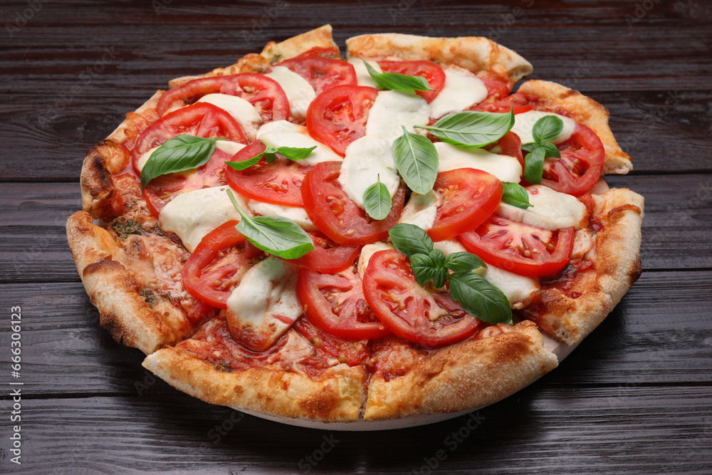 Delicious Caprese pizza with tomatoes, mozzarella and basil on dark wooden table, closeup