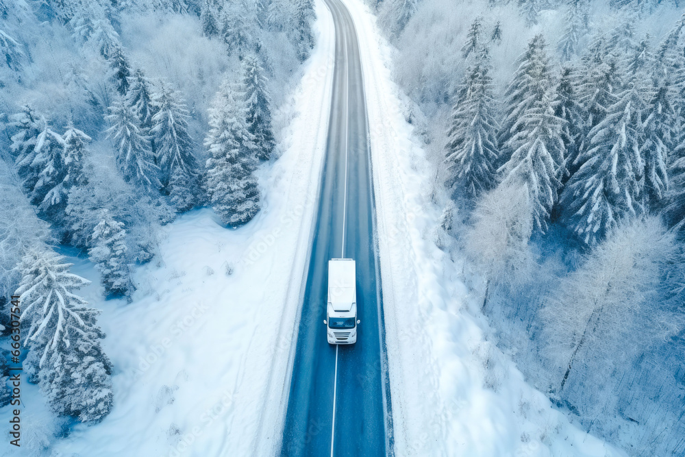 Aerial view of a semi truck moving on the winding winter road with wet surface and snow