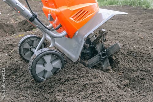 Electric cultivator for cultivating soil in vegetable garden. Side view.