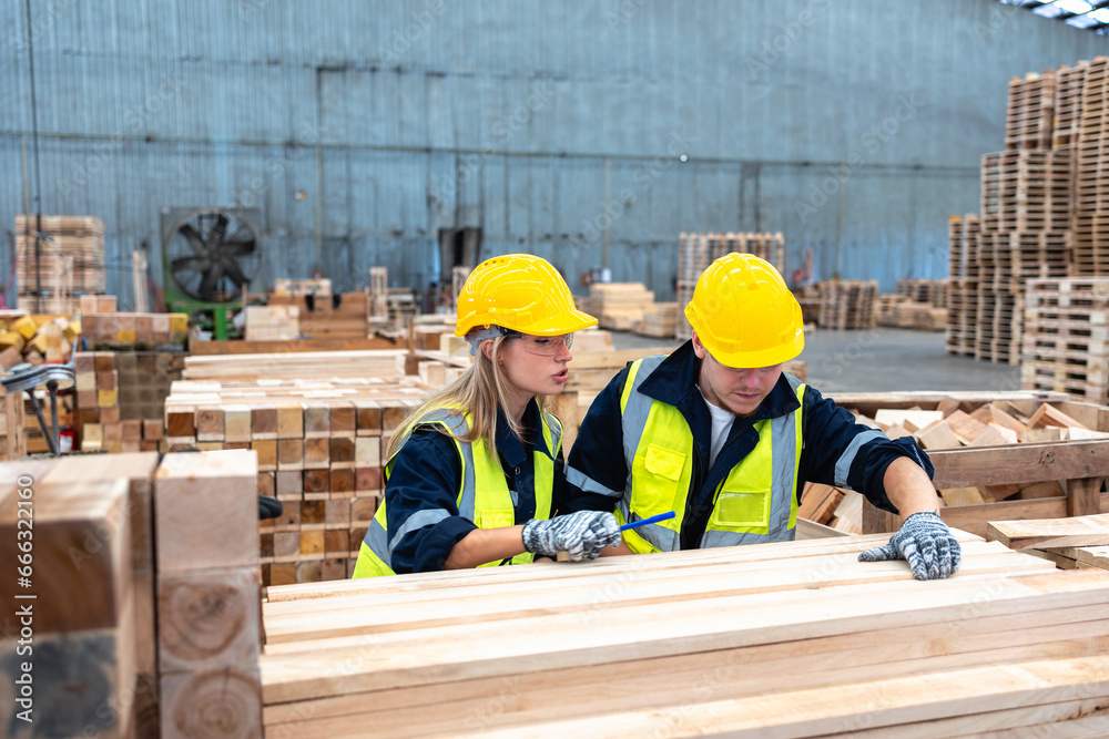 Two Caucasian Workers Inspecting Wood Quality in a Lumber Warehouse