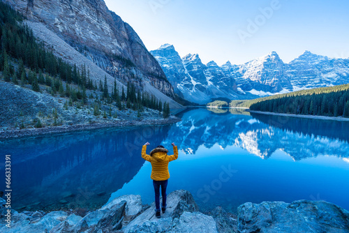  female backpacker travels and hikes to the top of a mountain, standing and admiring the view of Moraine lake in Banff National park.