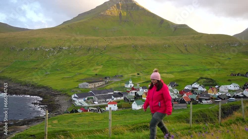 Woman hiking near the beautiful Gjogv Village and mountains in Eysturoy, Faroe Islands photo