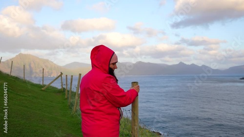 Wallpaper Mural Woman with red hood jacket holding on to stick due to intense wind in Gjogv, Faroe Islands Torontodigital.ca