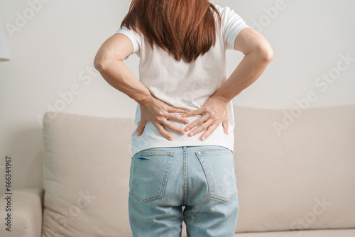woman having back body ache during sitting on Couch at home. adult female with muscle pain due to Piriformis Syndrome, Low Back Pain and Spinal Compression. Office syndrome and medical concept