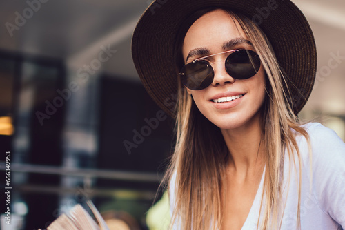 Stylish woman in sunglasses with open book looking at camera