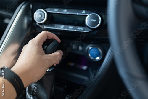Driver hand holding transmission shift gear. The driver shifts into gear to drive and travel, Automotive concept.