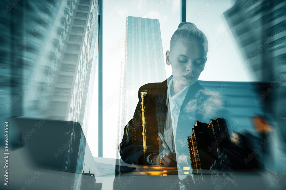 Obraz na plátně Young businesswoman silhouette using laptop while sitting at desk in creative corporate interior with windows and city view