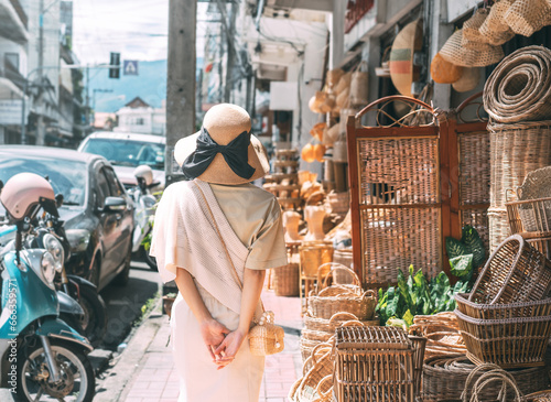 Behind traveler asian woman travel and shopping at wicker souvenir shop at local street Chiang Mai, Thailand