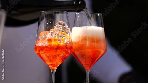 Apperol Spritz cocktail. 4k video while a bartender prepares two glasses of two Apperol Spritz drinks and pours prosecco over it.