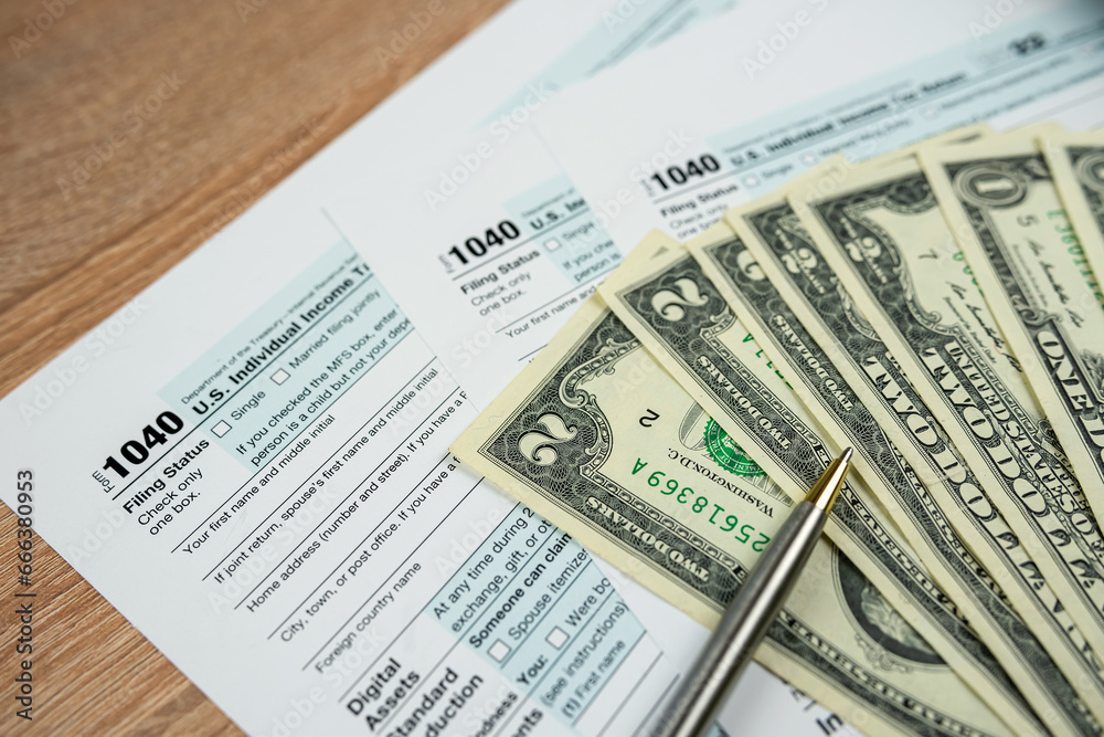 Tax payment with 1040 form pen and dollar bills Tax payment with 1040 form pen and dollar bills
