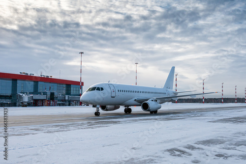 White passenger airplane taxiing on the airport apron at winter