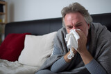 A sick man blows his nose with a handkerchief in the living room