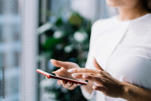 Smiling female using smartphone at workplace