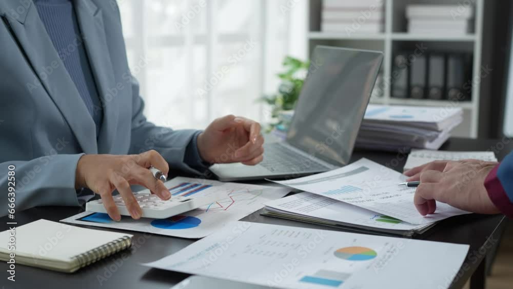 Finance business people or accountants point to the graph and use a calculator to calculate company income, expenses, taxes, and employee bonuses for Next year's improvement plan Finance business people or accountants point to the graph and use a calculator to calculate company income, expenses, taxes, and employee bonuses for Next year's improvement plan
