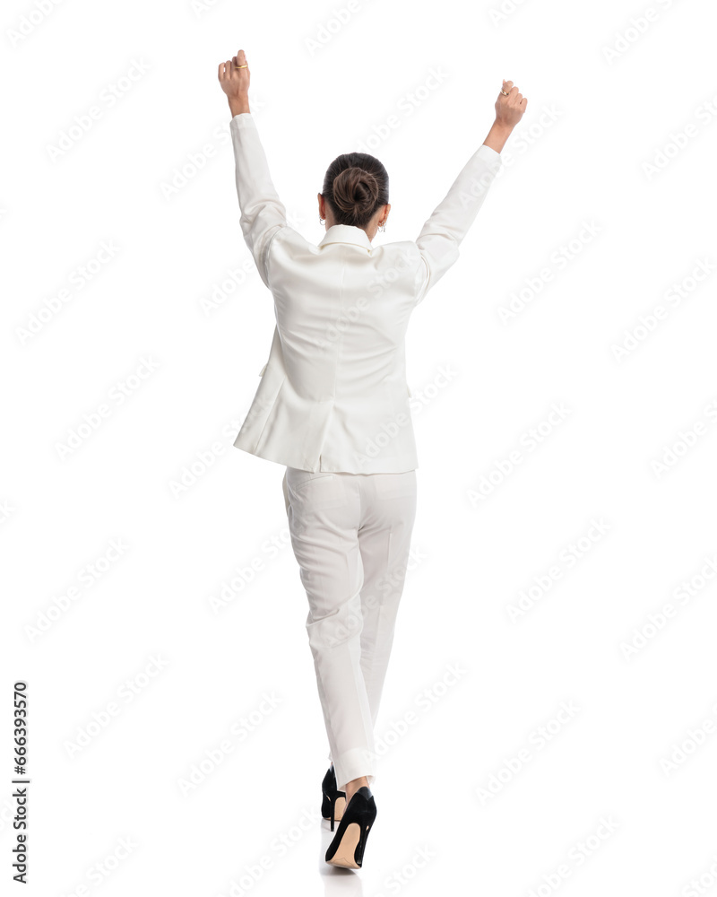 back view of elegant woman in white suit holding arms up and cheering back view of elegant woman in white suit holding arms up and cheering