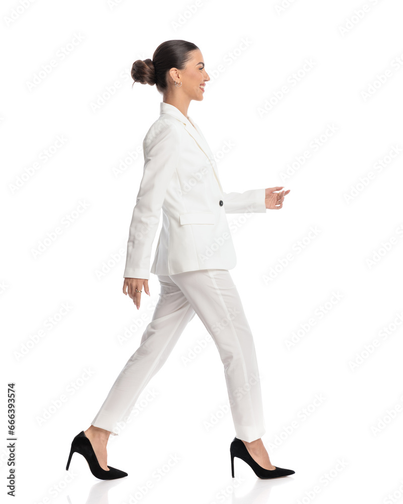 side view of elegant businesswoman with bun smiling and walking side view of elegant businesswoman with bun smiling and walking