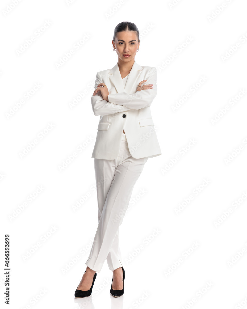 confident young woman in white suit crossing arms and looking forward confident young woman in white suit crossing arms and looking forward