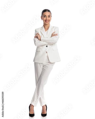 excited elegant girl in white suit folding arms and smiling