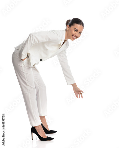side view of happy woman in suit holding hand in pocket and bending