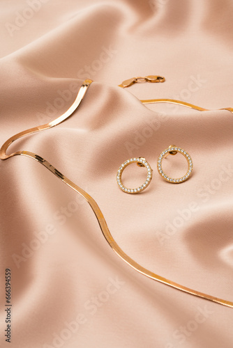 Golden chain necklace and earrings on silk background