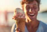 Male tourist holding an ice cream cone at the sea in the daytime