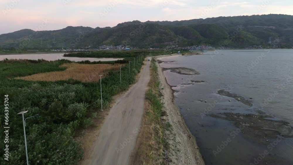 Aerial view of vehicles driving on a road crossing the Limboto Lake. aerial view of a lake experiencing drought
Aerial view of vehicles driving on a road crossing the Limboto Lake. aerial view of a lake experiencing drought