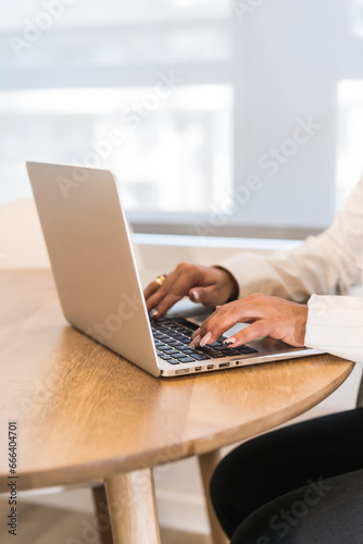 Woman's hands working on laptop at wooden table