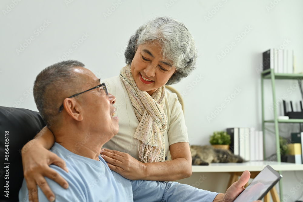 Lovely senior couple talking and watching video on digital tablet together. Elderly and technology concept Lovely senior couple talking and watching video on digital tablet together. Elderly and technology concept