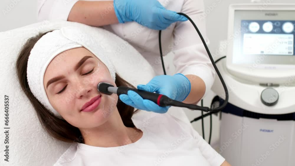 Close-up of a young woman's face during microcurrent therapy. Procedure for electrical stimulation of the face, rejuvenation, anti-wrinkle. The concept of youth and modern cosmetology technologies. Close-up of a young woman's face during microcurrent therapy. Procedure for electrical stimulation of the face, rejuvenation, anti-wrinkle. The concept of youth and modern cosmetology technologies.