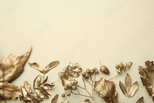 Beautiful golden leaves, berries and acorn on beige background, flat lay with space for text. Autumn decor © New Africa