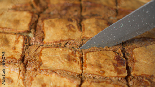 Cutting pie prepared at home with knife into portions, close-up, slight camera movement.