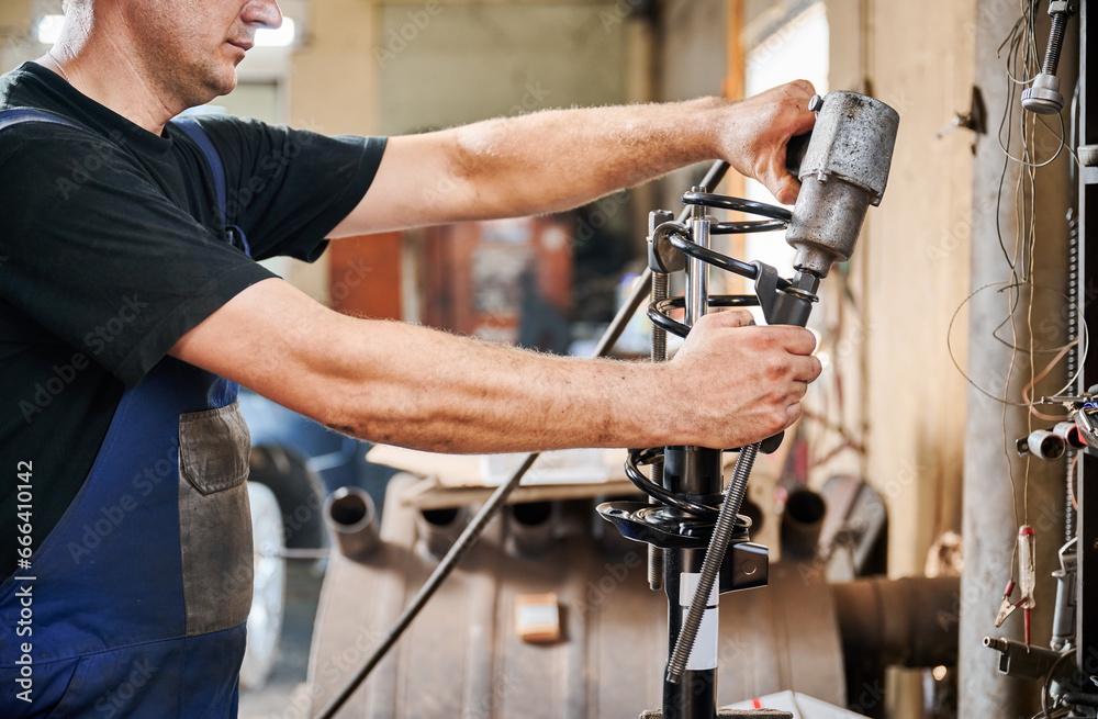 Cropped view of professional worker, repairman, mechanic working in garage, workshop. Man holding, using equipment, instrument. Concept of manual labor. Cropped view of professional worker, repairman, mechanic working in garage, workshop. Man holding, using equipment, instrument. Concept of manual labor.