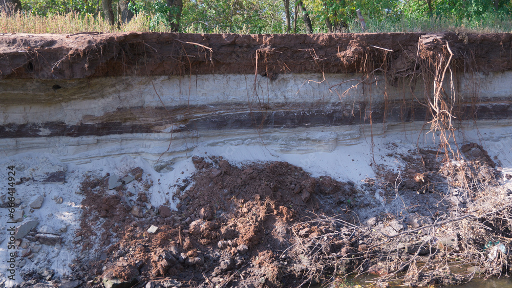 Coastline erosion, layered soil consisting of black soil and sand. Coastline erosion, layered soil consisting of black soil and sand.