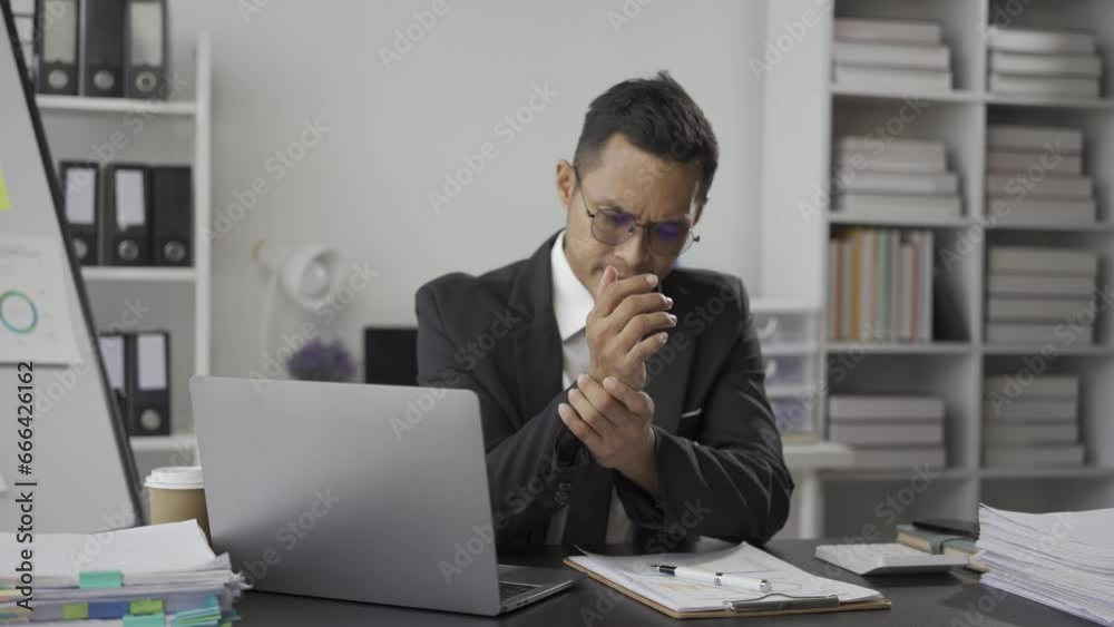 Asian businessman relaxes pain, tired from work, tired, sleepy and bored from sitting at a desk for a long time and office syndrome man stretches his arms to relax and take a break in the office. Asian businessman relaxes pain, tired from work, tired, sleepy and bored from sitting at a desk for a long time and office syndrome man stretches his arms to relax and take a break in the office.