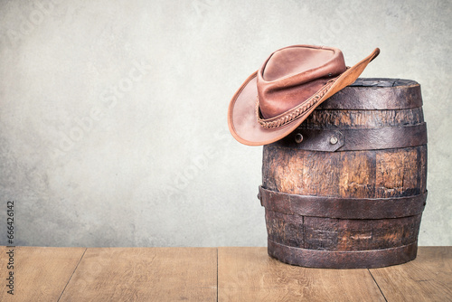 Wild West old retro leather cowboy hat and aged antique oak barrel. Vintage style filtered photo