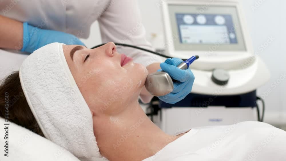 Cosmetologically ultrasonic facelift. A young woman enjoys a procedure at a cosmetology beauty center. Facelift, youth and healthy skin. Cosmetologically ultrasonic facelift. A young woman enjoys a procedure at a cosmetology beauty center. Facelift, youth and healthy skin.