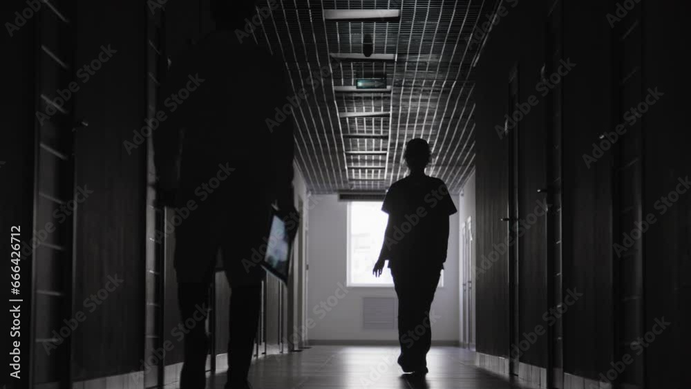 Full black and white shot of doctor and nurse passing by each other in hospitals hallway Full black and white shot of doctor and nurse passing by each other in hospitals hallway