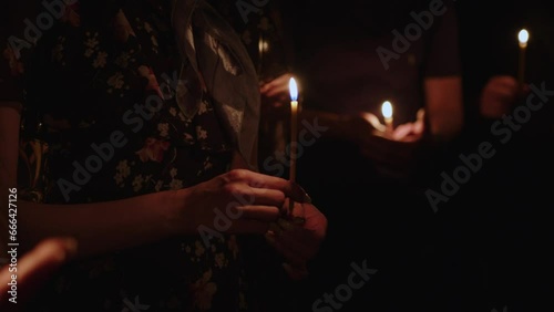 Young girls hold church candles in their hands while praying in the dark. Praying to God. Christians during the night vigil. Religion and prayers. Slavs praying to god. Young Christians. Human palm